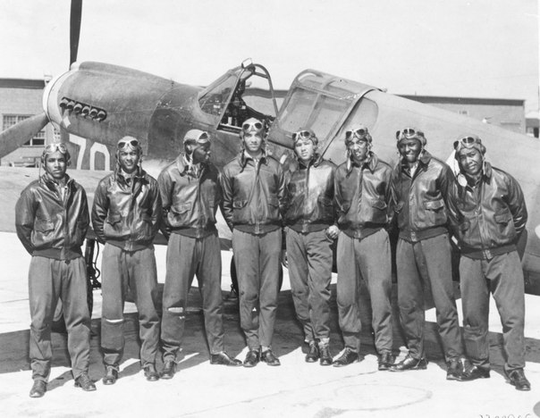 Чернокожие американские пилоты 99-й эскадрильи, более известной, как «Пилоты из Таскиги» на фоне самолета-истребителя P-40.